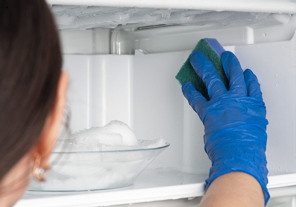 girl-washes-freezer-cleaning-refrigerator