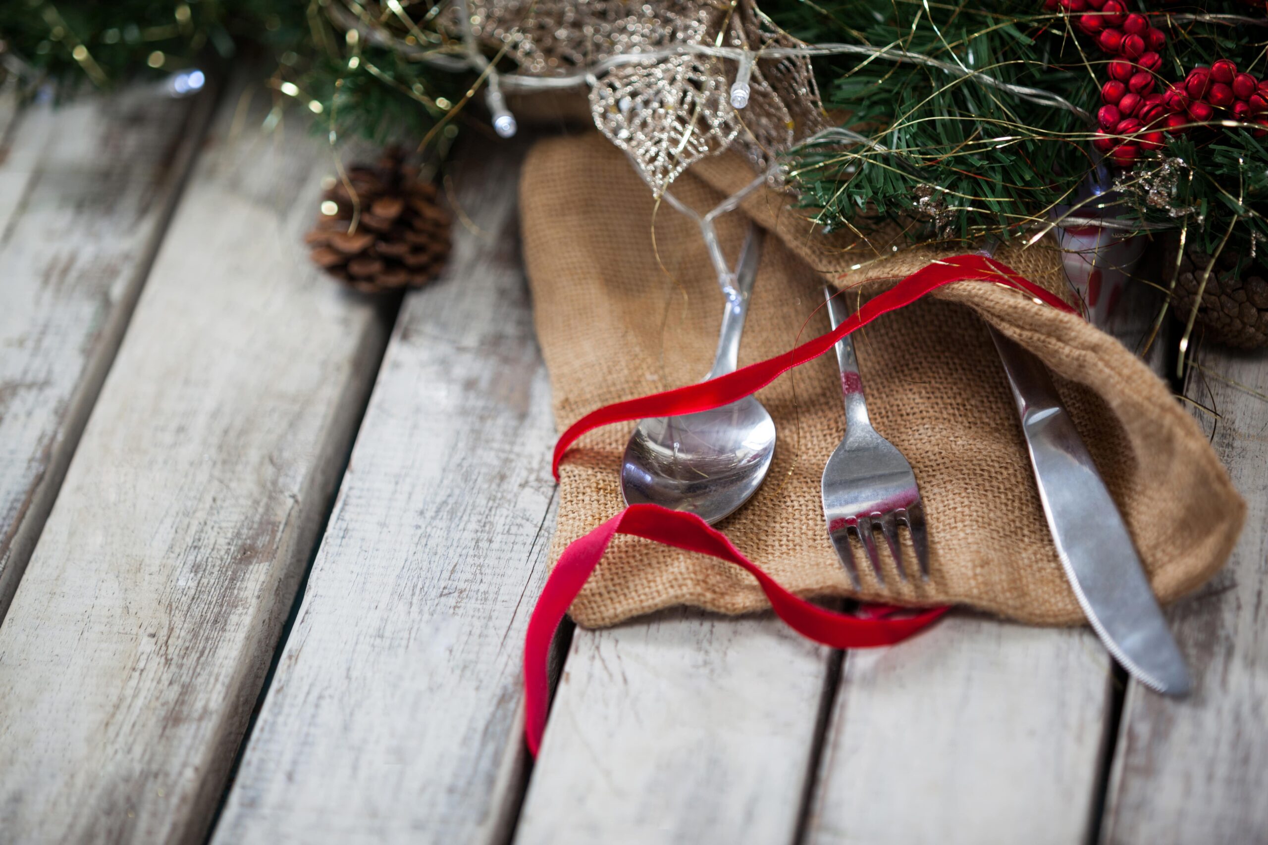 cutlery-wrapped-with-christmas-motif-wooden-table-min