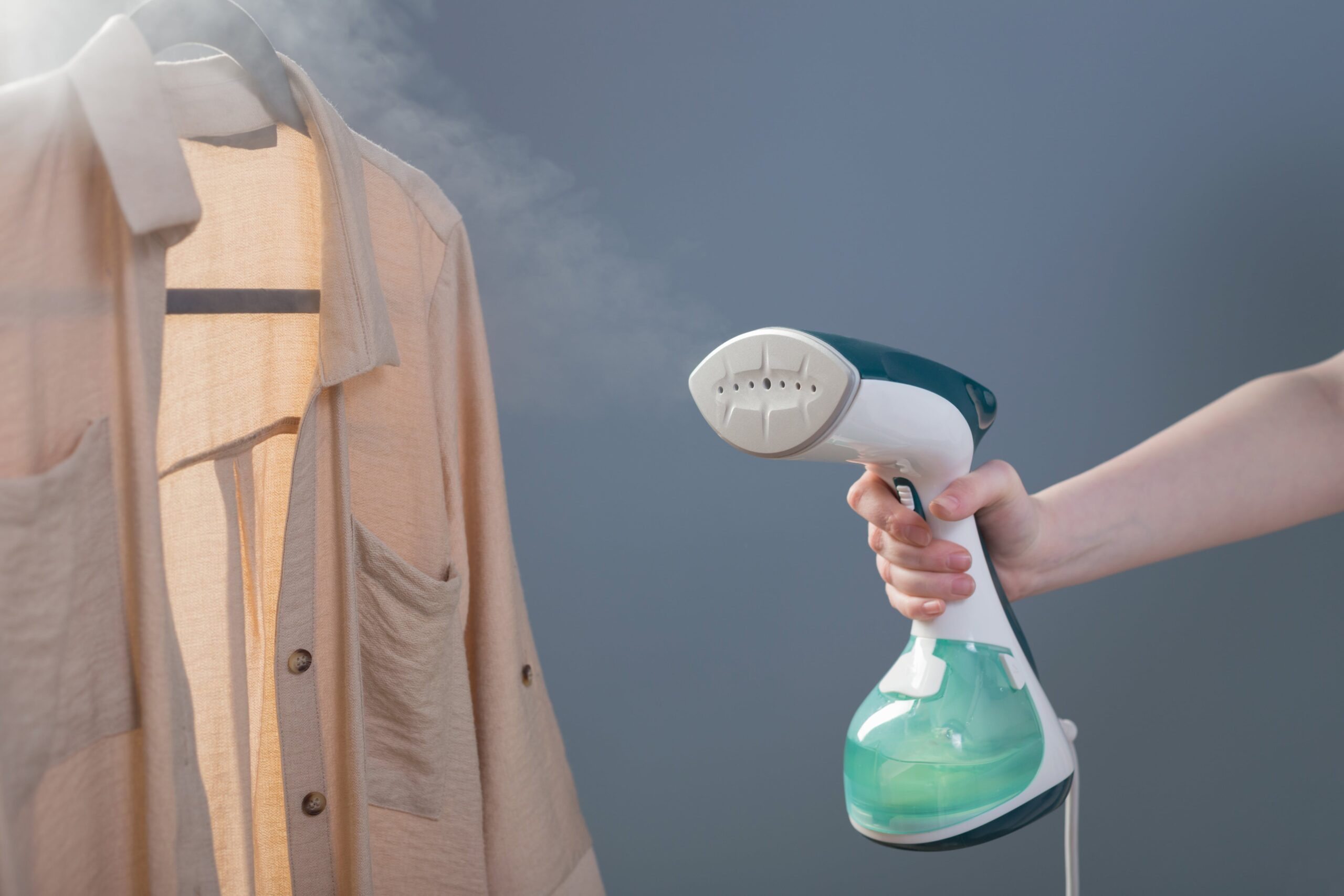 female-hand-with-steamer-shirt-blue-background-min