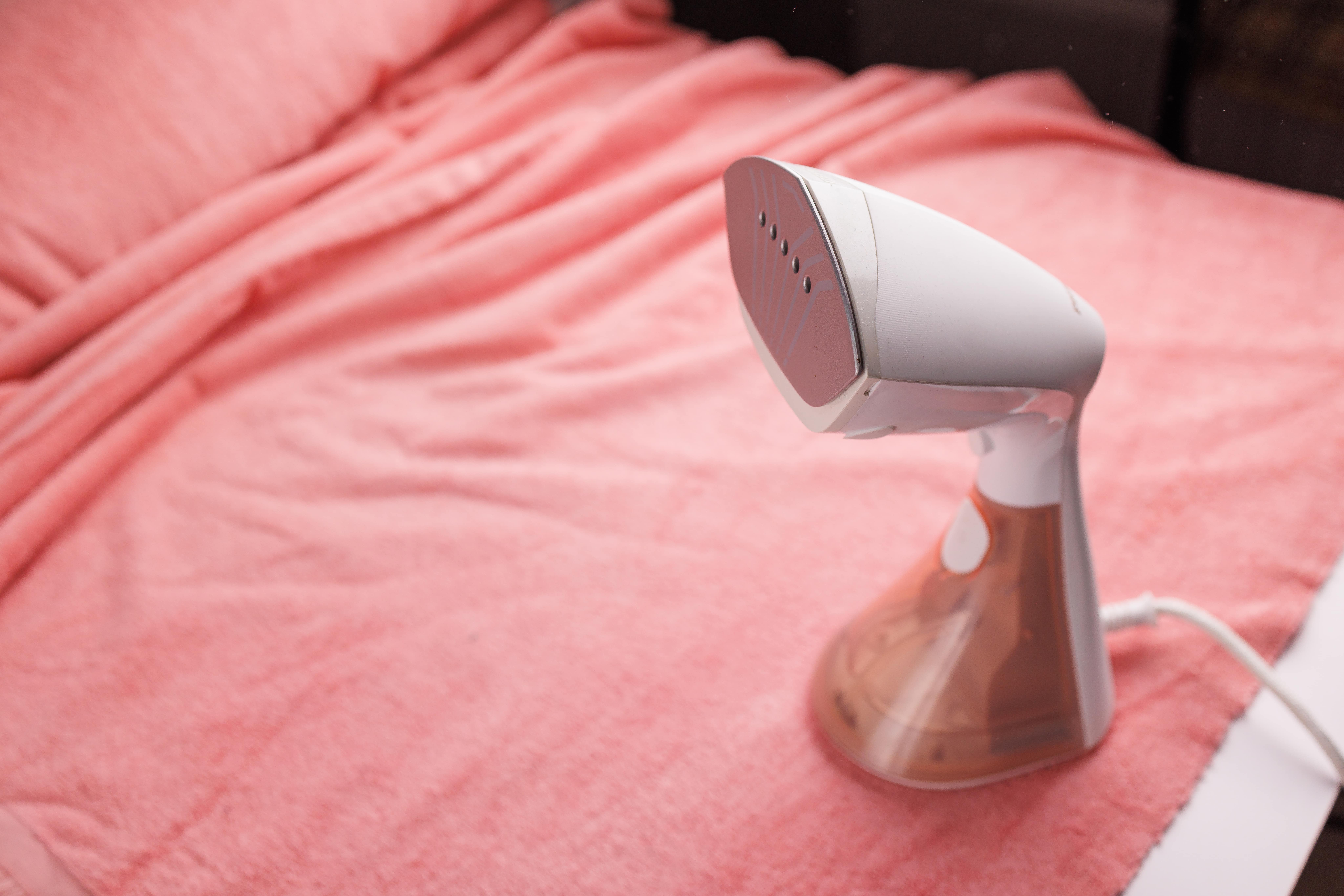 girl-smoothing-fabric-with-clothes-steamer-min (1)