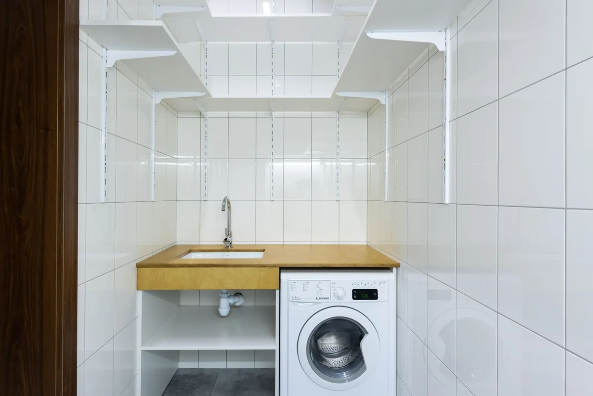 Lave-linge installé sous un plan de travail dans une buanderie