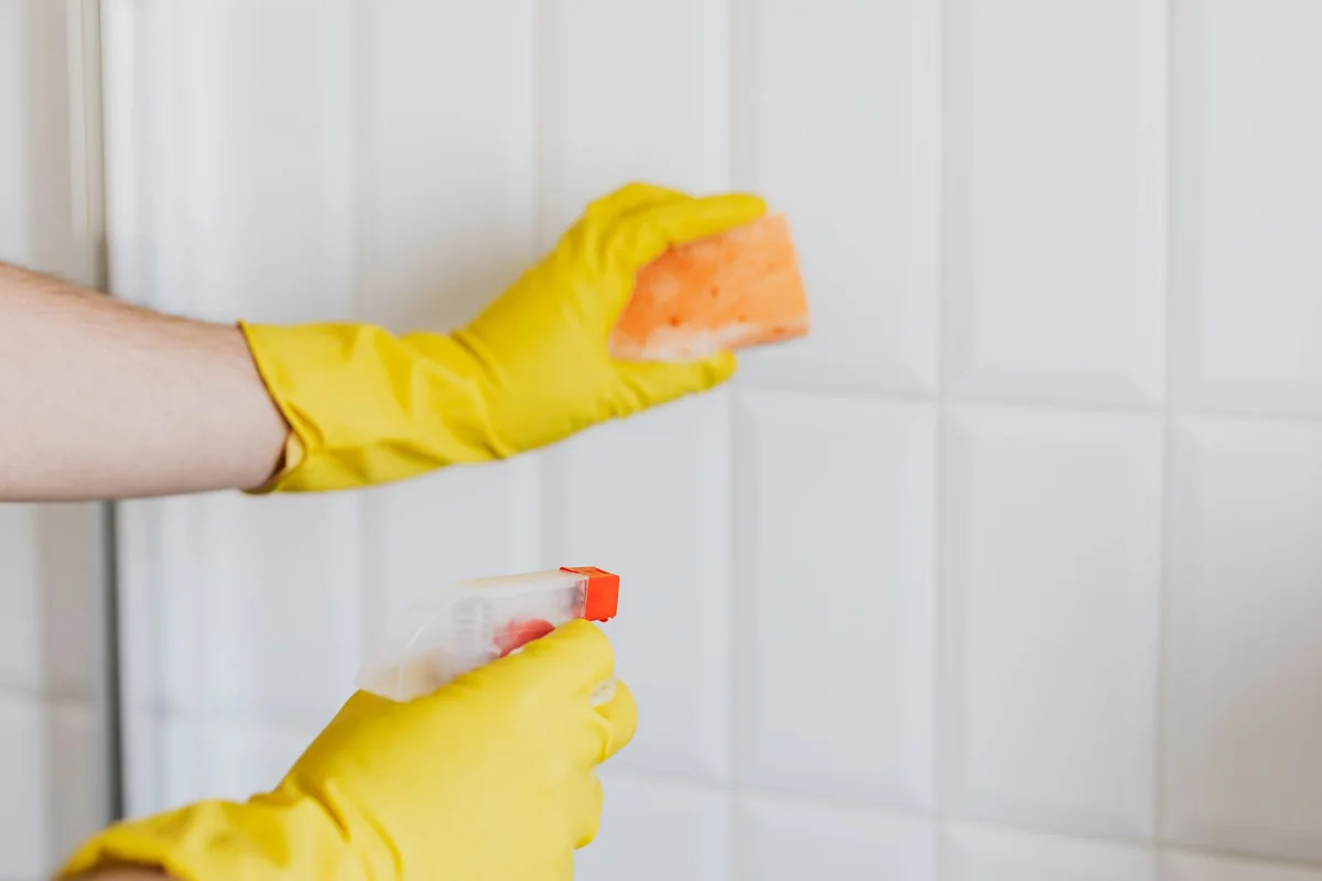 Nettoyage d'un mur carrelé avec gants et éponge