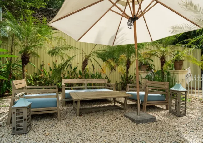 Salon de jardin installé sous un parasol dans un jardin tropical