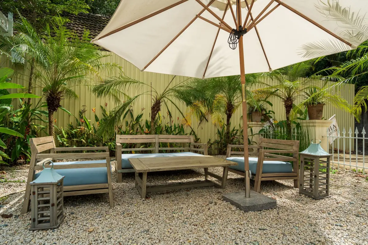Salon de jardin installé sous un parasol dans un jardin tropical