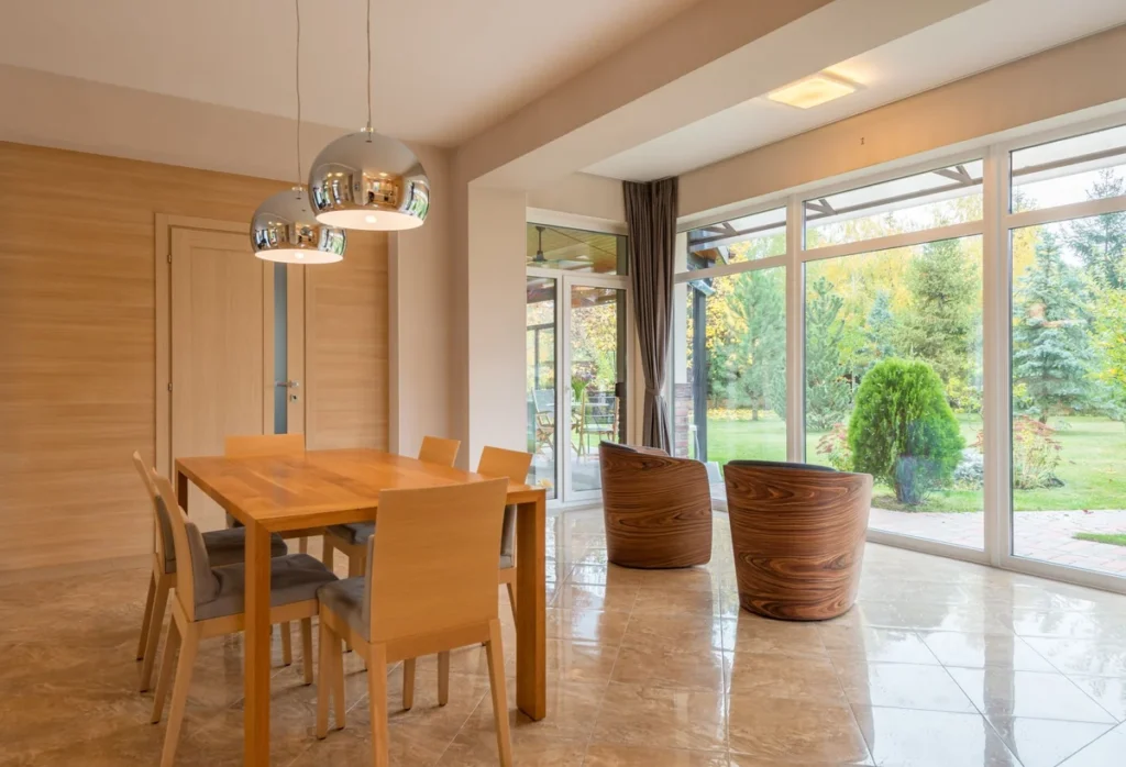 Table de salle à manger en bois devant une grande baie vitrée