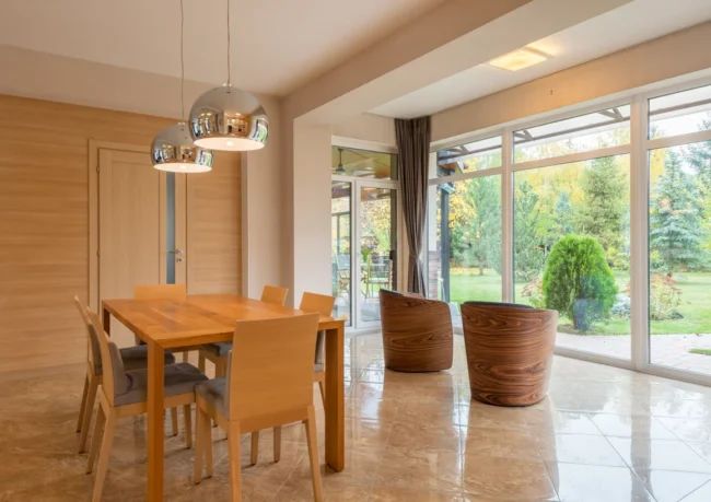 Table de salle à manger en bois devant une grande baie vitrée