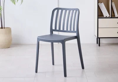 Chaise SORA en polypropylène gris anthracite, dossier ajouré à lattes verticales, dans une pièce lumineuse