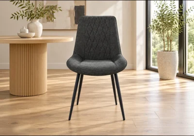 Chaise VANEA en tissu gris anthracite surpiqué en losanges, pieds en métal noir, vue de face dans une salle à manger lumineuse