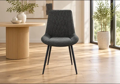 Chaise VANEA en tissu gris anthracite surpiqué en losanges, pieds en métal noir, vue de face dans une salle à manger lumineuse